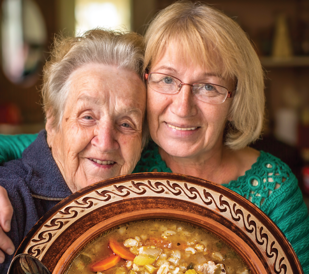 A senior resident with her adult daughter enjoying a bowl of soup to go.
