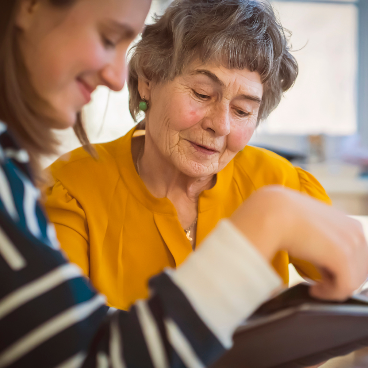 Senior woman and caretaker looking at a photo album